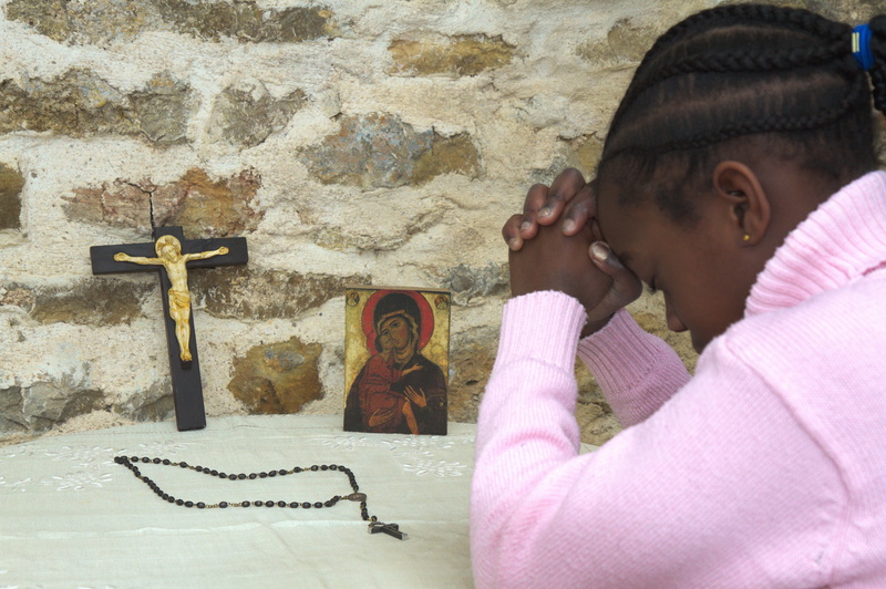 femme qui prie avec un crucifix, un chapelet et une icône de la vierge Marie