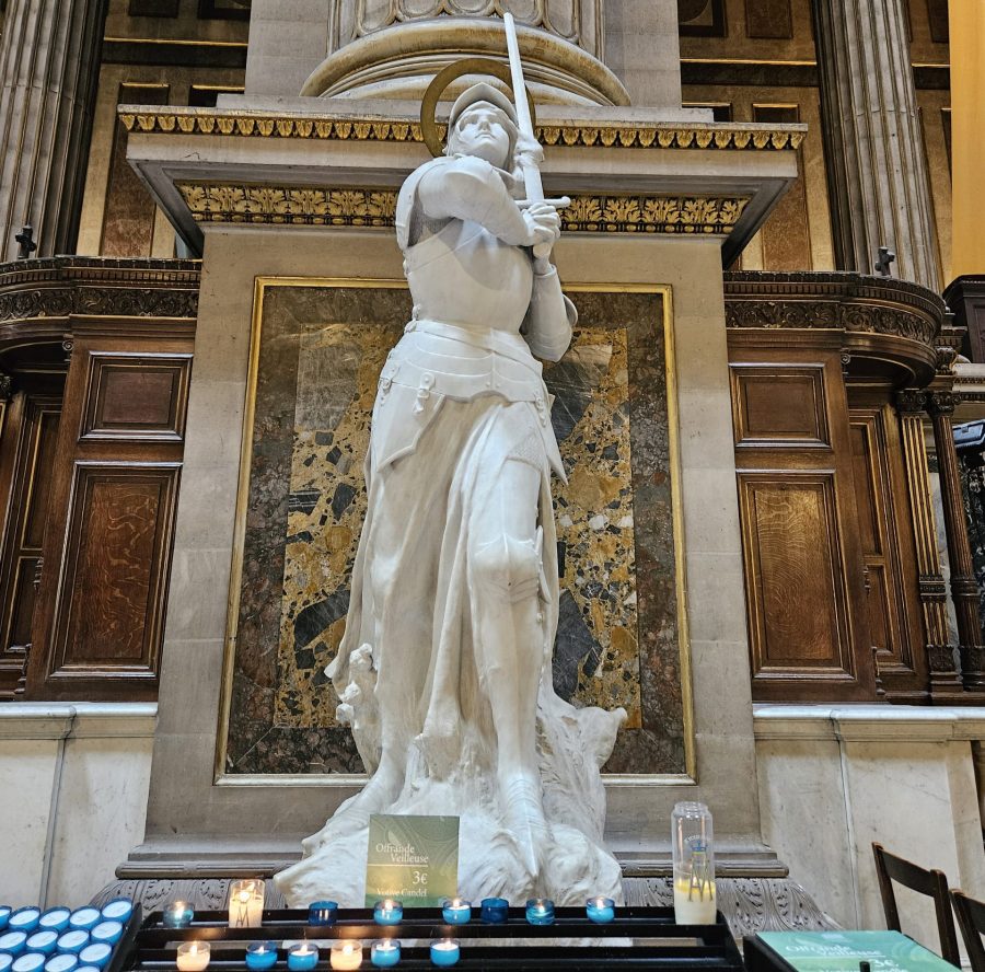 Statue de Sainte Jeanne d'Arc avec des bougies symbolisant la prière des gens