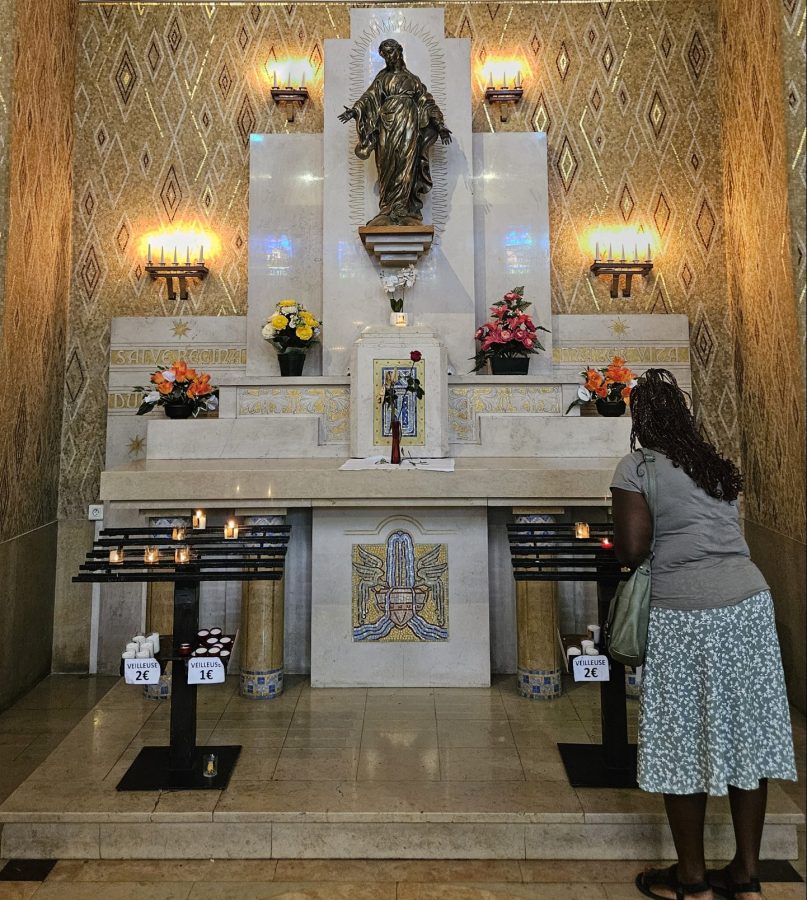 Femme allumant une bougie devant une statue de Marie pour faire une prière d'intercession aux saints