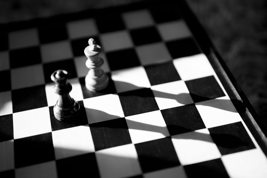 un pion d'échec blanc et un autre noir posés sur un damier représentant le double effet du moindre mal